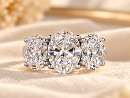 Oval trellis engagement ring with three lab-grown diamonds and pave accents, front view on cream fabric