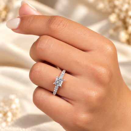 Princess cut diamond pavé engagement ring worn on a finger, side angle
