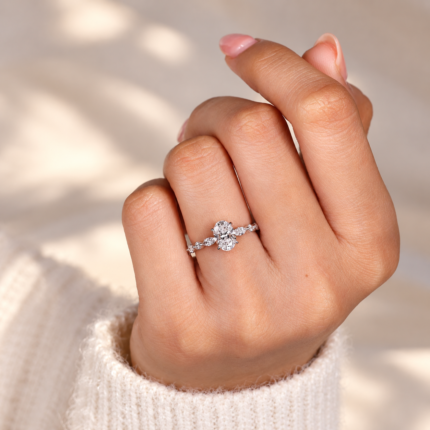 Oval diamond accent ring worn on curled fingers
