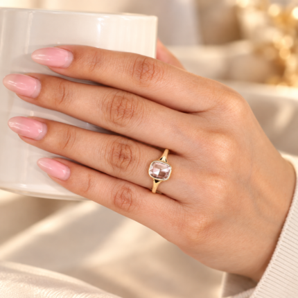 Cushion rose cut diamond ring worn on a hand resting on cream fabric