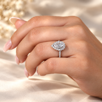 Pear halo engagement ring worn on curled fingers