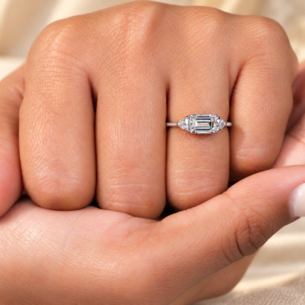 East west emerald lab diamond ring with trillion side stones, worn above the knuckles