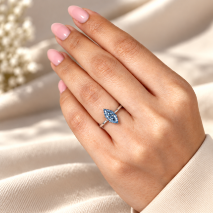 Blue marquise solitaire on an open hand for scale