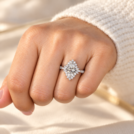Marquise halo ring on a hand beside cream knit fabric