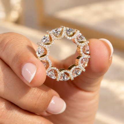 Micro pave eternity band held between fingers, showing triangular stones around the full circle