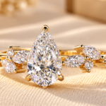 Pear diamond cluster ring with marquise and round side diamonds on a yellow gold tone band, front view