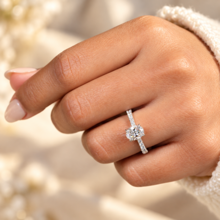 Oval diamond tapered pavé ring on a curled hand