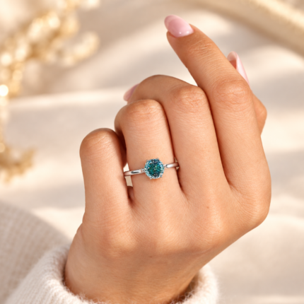 Angled close-up of blue Portuguese moissanite ring worn on a finger